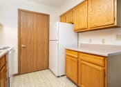 Thumbnail 5 of 12 - A kitchen with a white fridge and wooden cabinets.