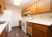Thumbnail 1 of 12 - A kitchen with white appliances and wooden cabinets.