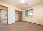 Thumbnail 8 of 12 - A room with a carpeted floor and a window showing trees outside.