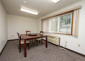 Thumbnail 11 of 12 - A room with a table and chairs and a window with blinds.