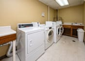 Thumbnail 10 of 12 - A row of washing machines in a laundry room.