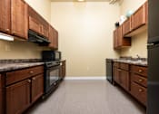 Thumbnail 2 of 17 - A kitchen with wooden cabinets and black appliances.