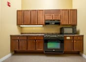 Thumbnail 1 of 17 - A kitchen with wooden cabinets and a black oven.