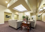 Thumbnail 13 of 17 - A living room with a couch, a table, and a skylight.