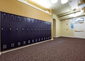 Thumbnail 7 of 17 - A row of dark blue lockers in a room with brown carpeting.