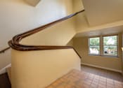 Thumbnail 14 of 17 - A staircase with a wooden handrail and tiled floor.