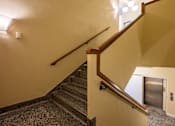 Thumbnail 15 of 17 - A staircase with a wooden handrail and a metal handrail.