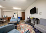 Thumbnail 5 of 20 - A living room with a grey couch and a blue armchair.