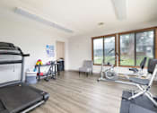 Thumbnail 6 of 20 - A home gym with a treadmill, exercise bike, and other equipment.