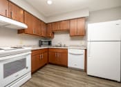 Thumbnail 10 of 20 - A kitchen with white appliances and wooden cabinets.