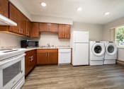 Thumbnail 8 of 20 - A kitchen with white appliances and wooden cabinets.