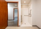Thumbnail 16 of 20 - A white bathroom with a wooden door.