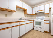Thumbnail 2 of 14 - A kitchen with white cabinets and a white oven.