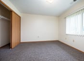Thumbnail 7 of 14 - A room with a carpeted floor and a window with blinds.