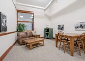 Thumbnail 18 of 18 - A living room with a brown couch, wooden coffee table, and a dining table with chairs.