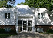 Thumbnail 1 of 11 - A white building with a black door and windows.