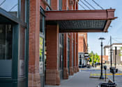 Thumbnail 2 of 21 - A red brick building with a black trash can in front of it.