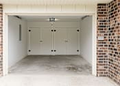 Thumbnail 11 of 11 - A garage with a white door and brick walls.