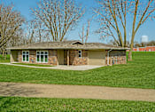 Thumbnail 2 of 11 - A house with a brown roof and a green lawn in front.