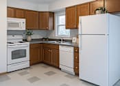 Thumbnail 6 of 11 - A kitchen with white appliances and brown cabinets.