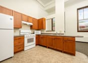 Thumbnail 6 of 19 - A kitchen with white appliances and wooden cabinets.