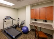 Thumbnail 19 of 19 - A treadmill, exercise ball, and stationary bike are in a room with a desk and cabinets.