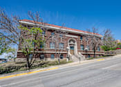 Thumbnail 3 of 19 - A large red brick building with a staircase leading to the front door.
