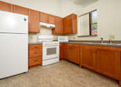 Thumbnail 7 of 19 - A kitchen with brown cabinets and white appliances.