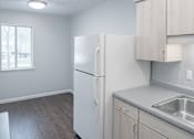 Thumbnail 2 of 6 - A kitchen with a white refrigerator, sink, and cabinets.