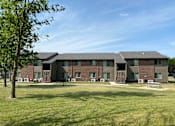 Thumbnail 1 of 10 - A large building with a green lawn in front.
