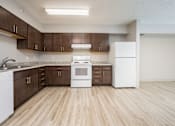 Thumbnail 6 of 14 - A kitchen with white appliances and brown cabinets.