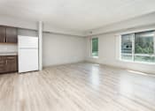 Thumbnail 8 of 14 - A spacious room with a white fridge and wooden flooring.