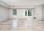 Thumbnail 9 of 14 - A spacious room with wooden flooring and two windows.