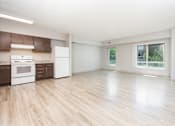 Thumbnail 7 of 14 - A kitchen with white appliances and wooden floors.