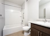 Thumbnail 12 of 14 - A white toilet sits next to a bathtub in a bathroom.