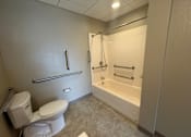 Thumbnail 22 of 28 - A white toilet sits next to a walk-in shower in a bathroom.