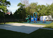 Thumbnail 4 of 11 - A basketball court with a basketball hoop and a playground with slides in the background.