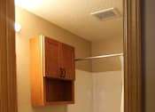 Thumbnail 10 of 11 - A white toilet sits in a bathroom with a wooden cabinet and a white sink.