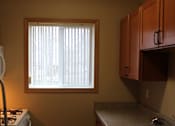 Thumbnail 6 of 11 - A small room with a window and a microwave above a stove.