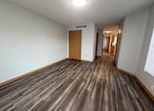 Thumbnail 6 of 11 - A long hallway with wood floors and a door at the end.