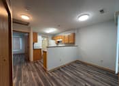 Thumbnail 3 of 11 - A room with wooden flooring and a kitchenette.