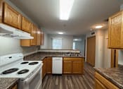 Thumbnail 4 of 11 - A kitchen with a white stove top oven and a white dishwasher.