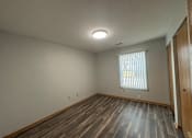 Thumbnail 8 of 11 - A room with wooden flooring and a window with blinds.