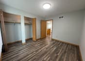 Thumbnail 7 of 11 - A room with wooden floors and a closet with a sliding door.