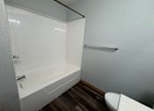 Thumbnail 10 of 11 - A white bathroom with a toilet and a bathtub.