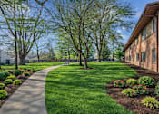 Thumbnail 20 of 20 - A walkway leads through a grassy area with trees and shrubs.