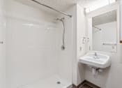 Thumbnail 19 of 20 - A white bathroom with a sink and a shower.