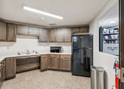 Thumbnail 8 of 20 - A kitchen with a black refrigerator and wooden cabinets.