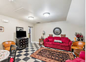 Thumbnail 6 of 17 - A living room with a red couch and a checkered floor.