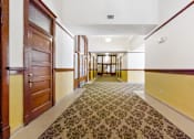 Thumbnail 3 of 17 - A hallway with a patterned carpet and wooden doors.